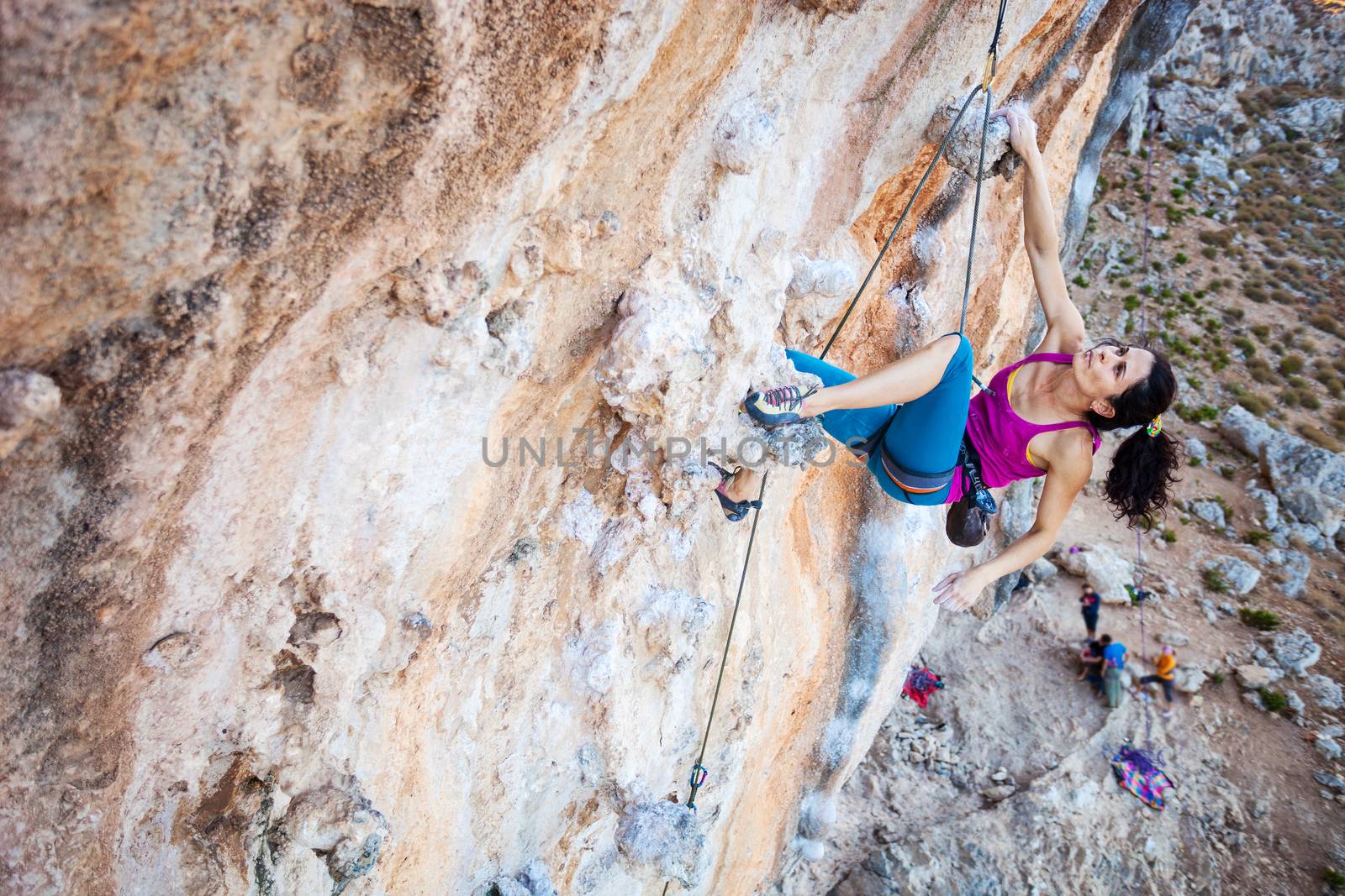 Young female rock climber on a cliff by photobac