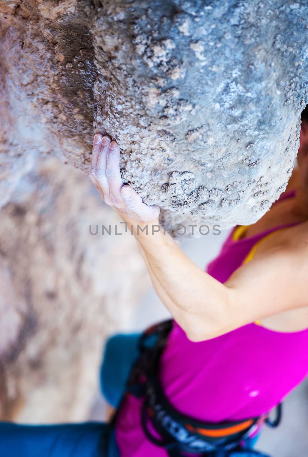 Cropped view of young woman climbing natural cliff, hand in focus