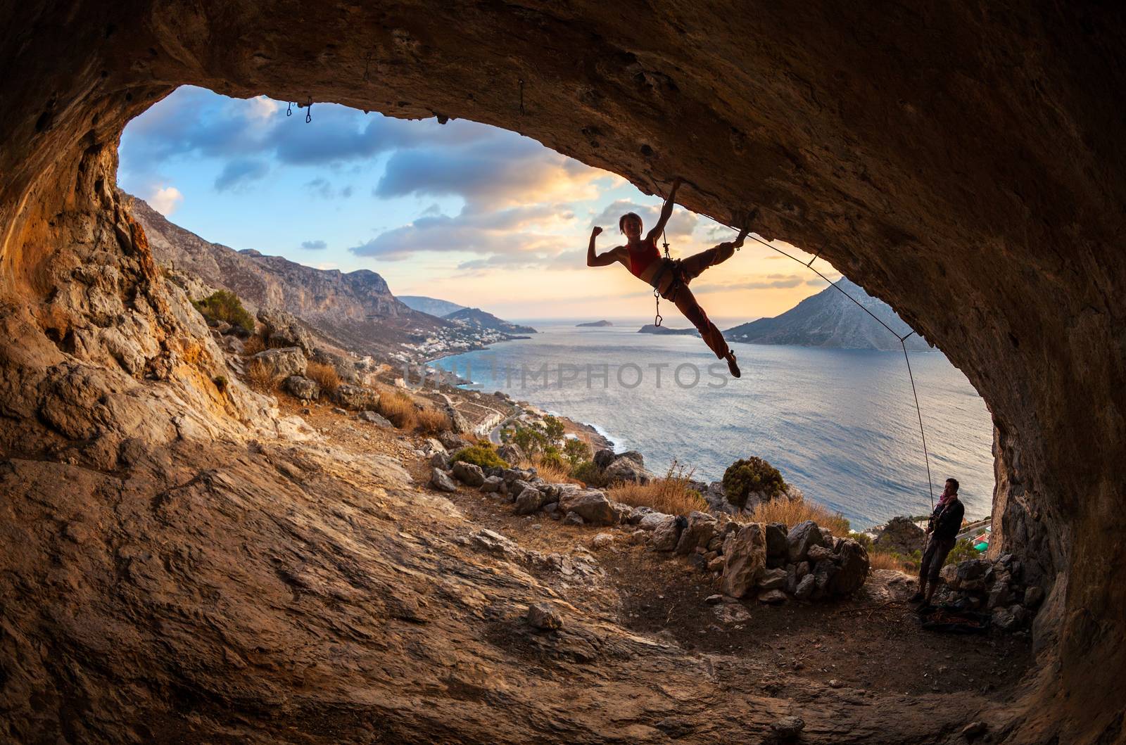 Female rock climber posing while climbing by photobac