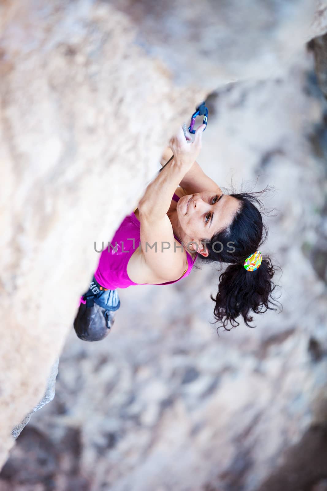 Young female rock climber on a cliff by photobac