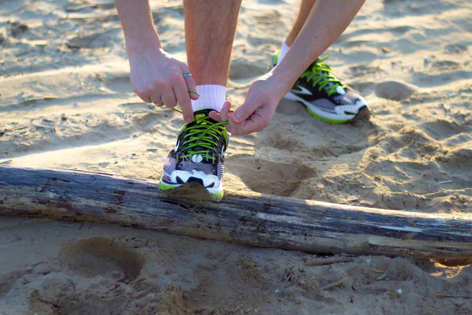 uomo in spiaggia che si allaccia le scarpe prima di un'attivit�� sportiva