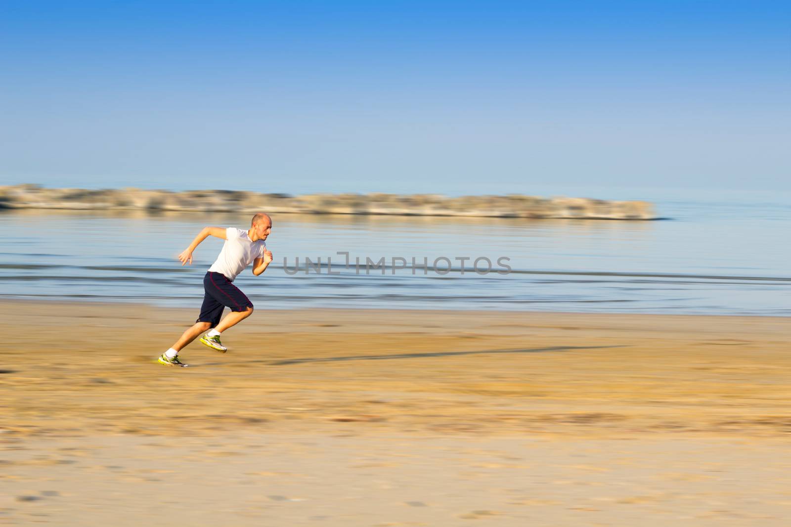 boy who trains running on the beach