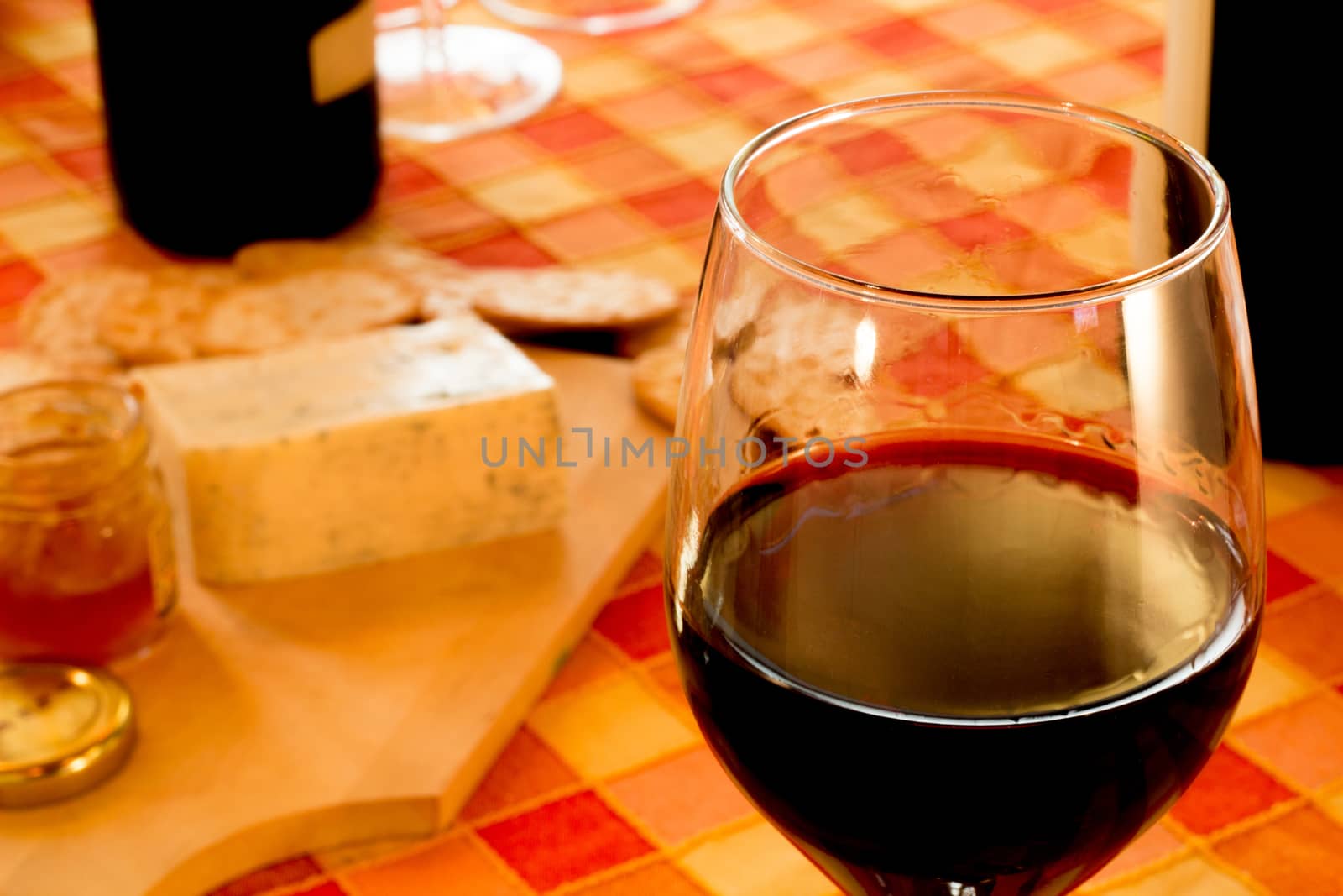 Glass of red wine, cheese, bread, in the rustic table