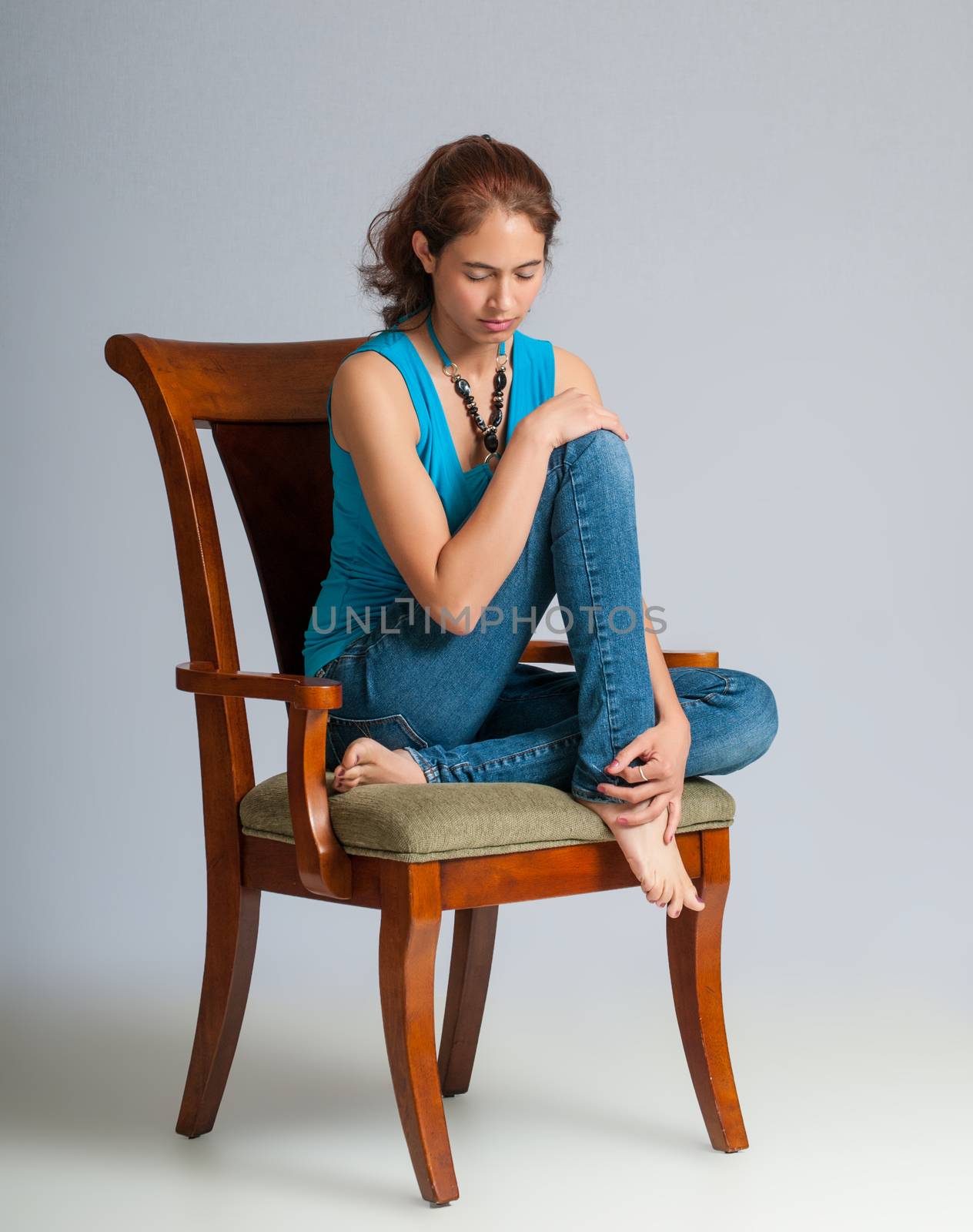 Pretty young brunette deep in thought as she sits in a padded arm chair.