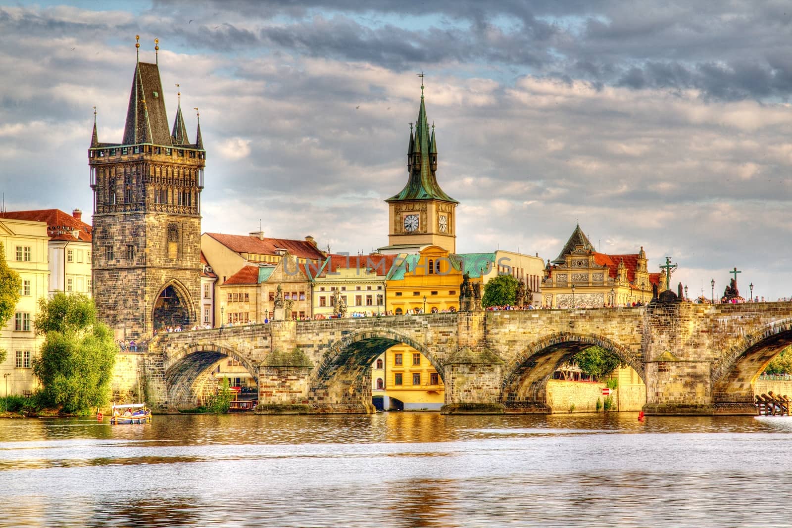 Photo shows the bridge, river and some old houses in Prague.