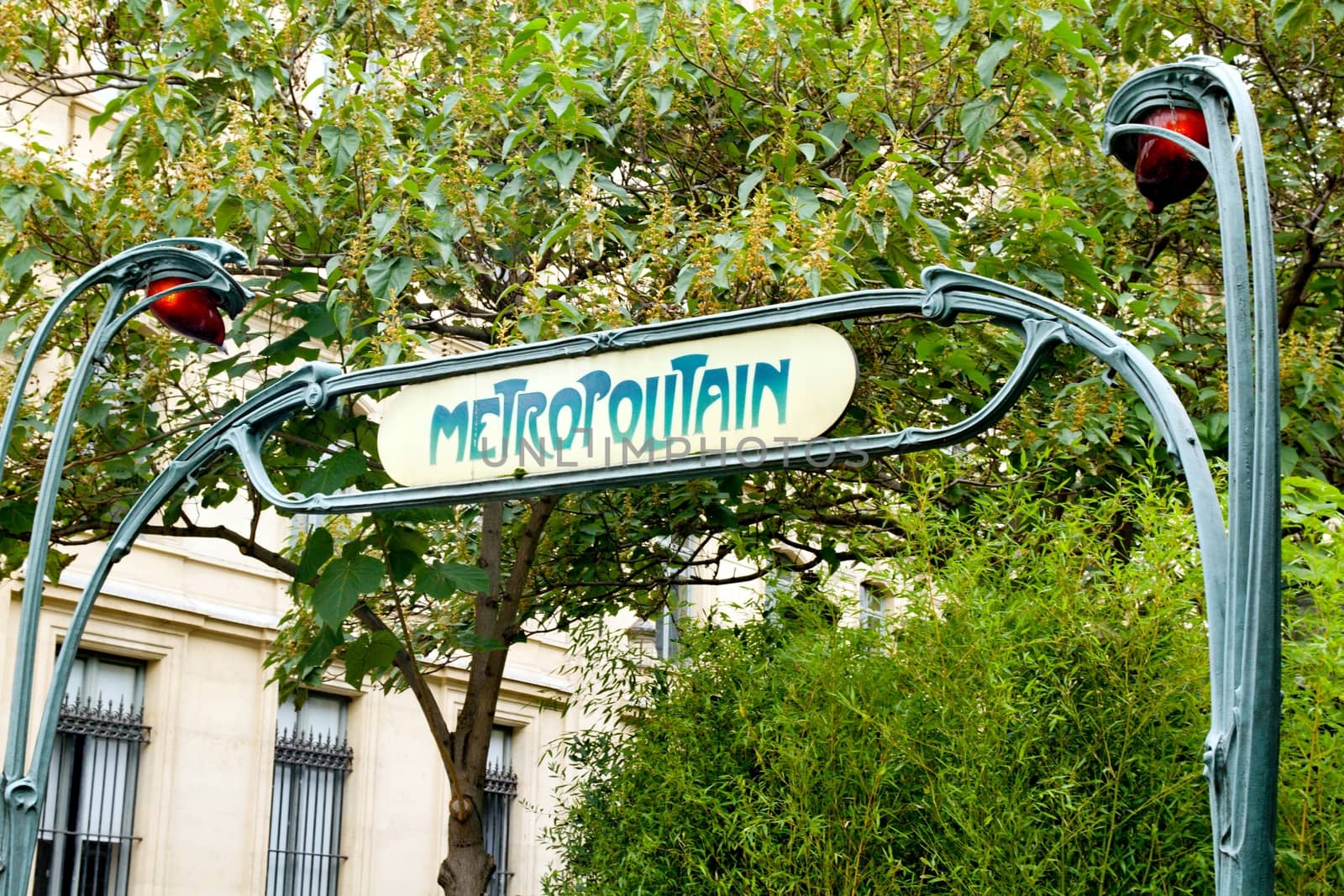 Photo shows old Parisian metro sign in front of the entrance.