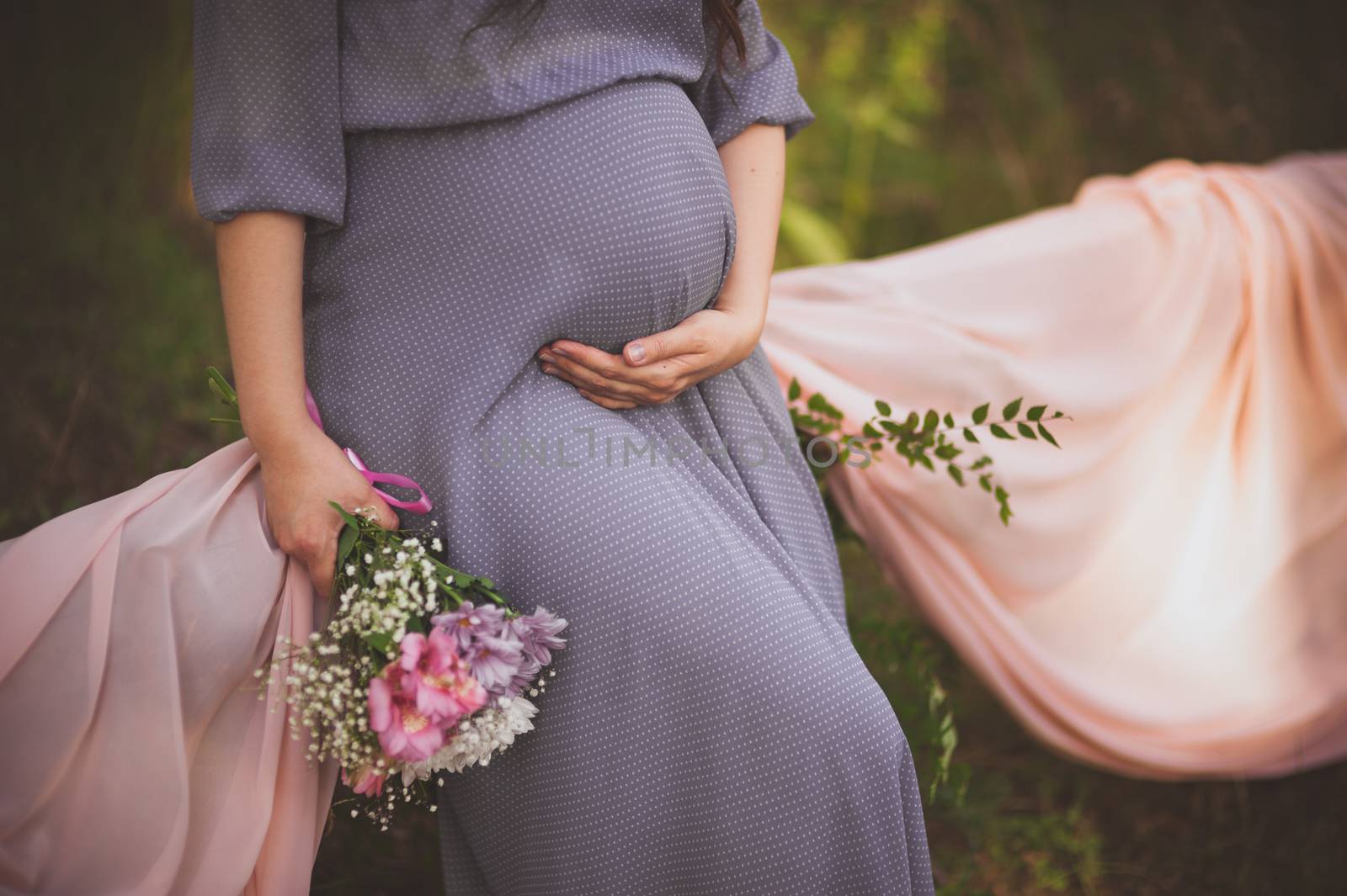 women holds hands on her belly while being pregnant  no face 