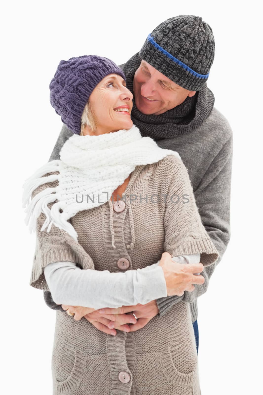 Happy mature couple in winter clothes embracing on white background