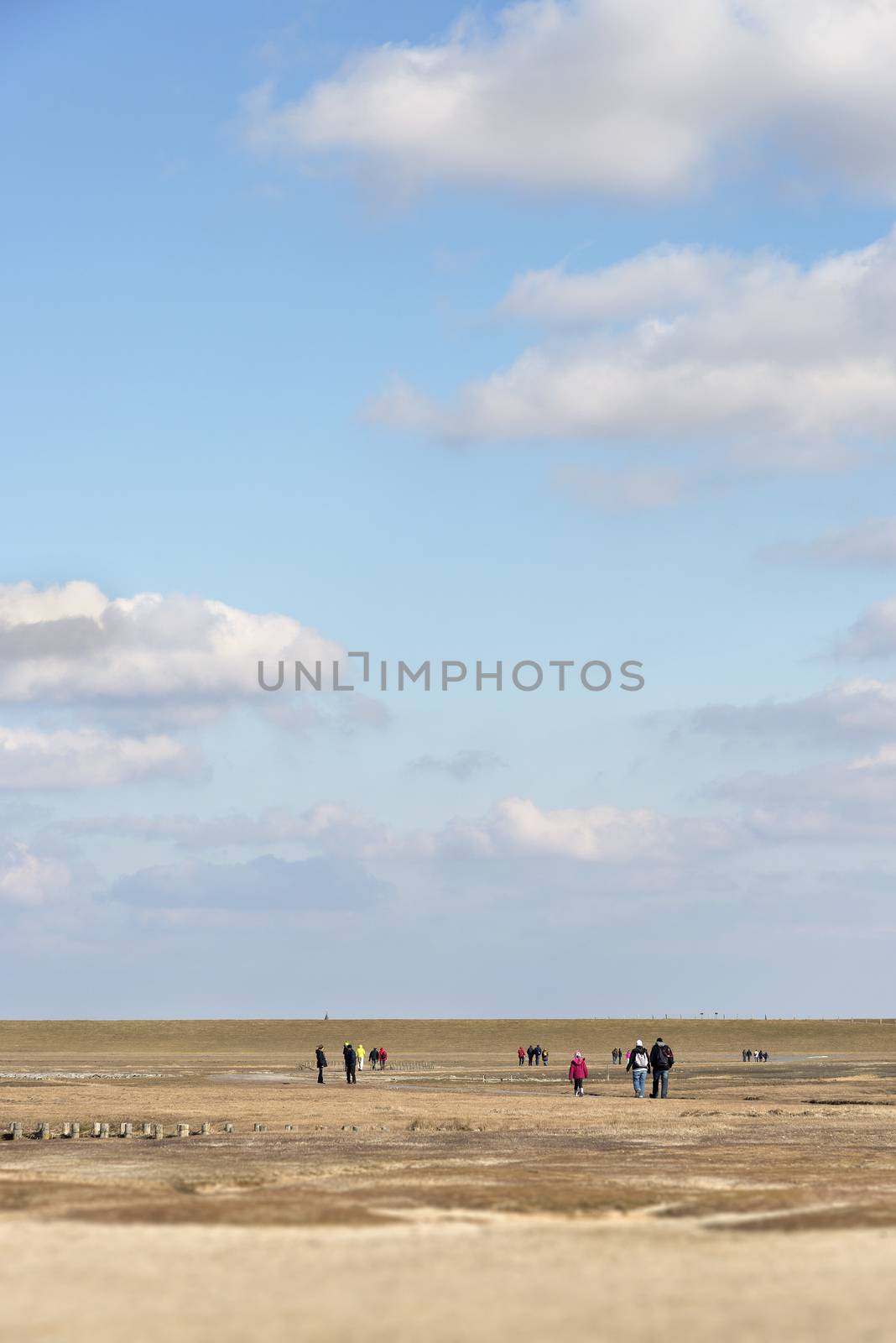 Image of a beach in northern Germany with hikers on a sunny and cold day in spring