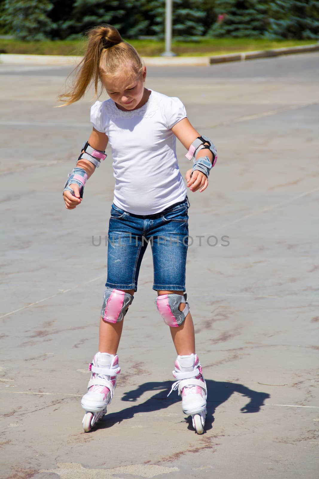 Learning girl on roller skates in summer