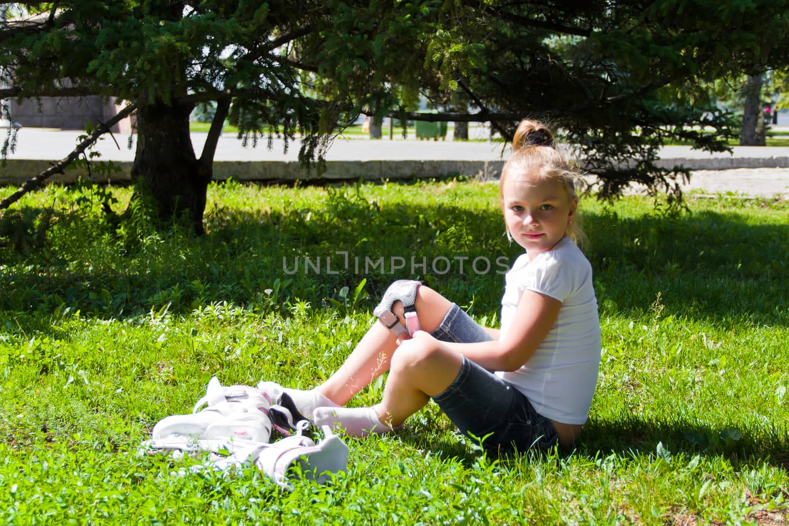 Cute girl put on roller skates in summer