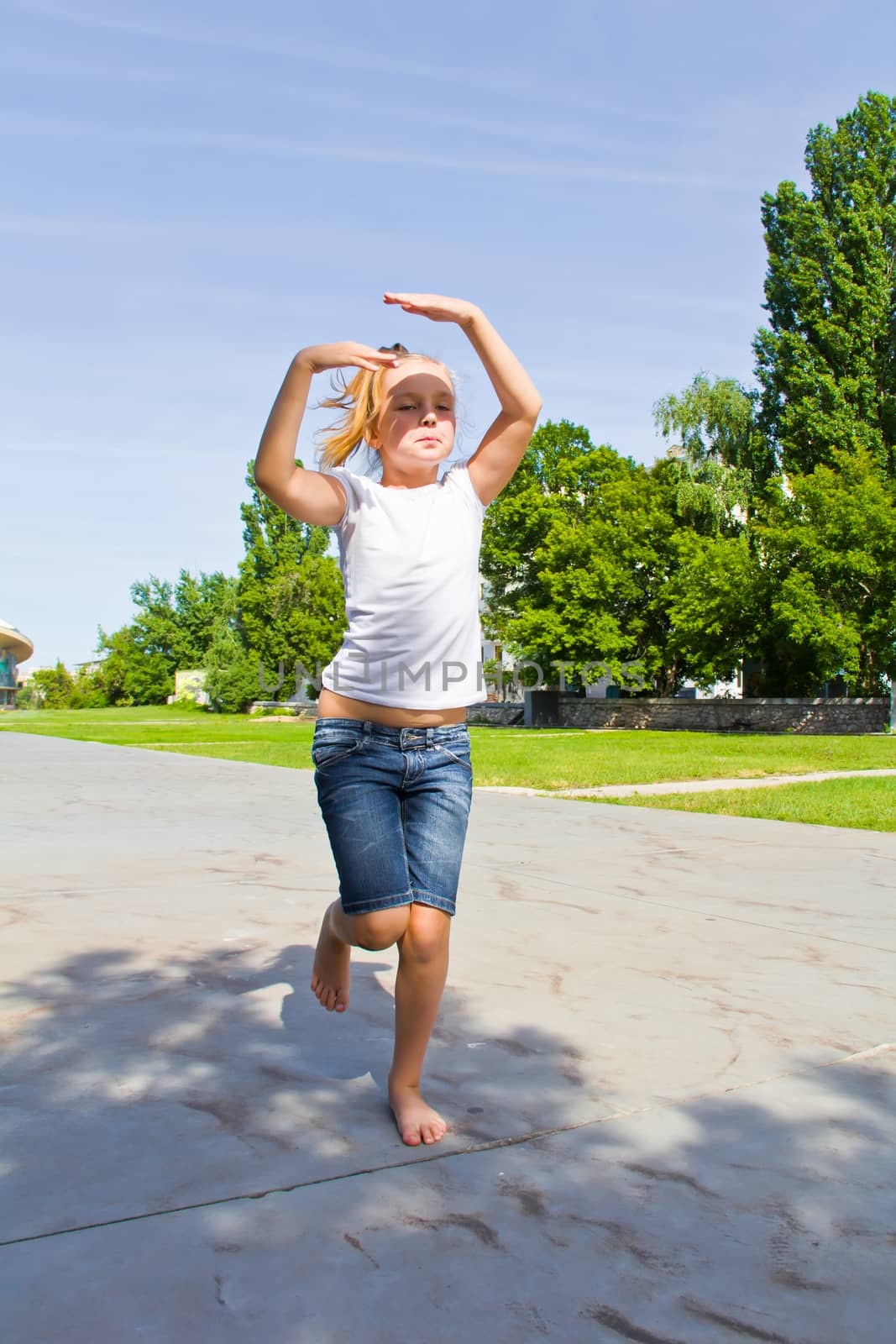 Cute girl with blond hair jumping on one leg