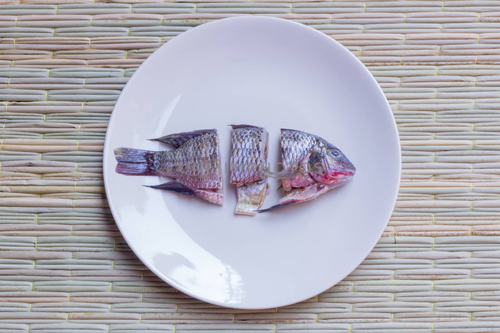 small choped fish in round dish,  on a traditional mat
