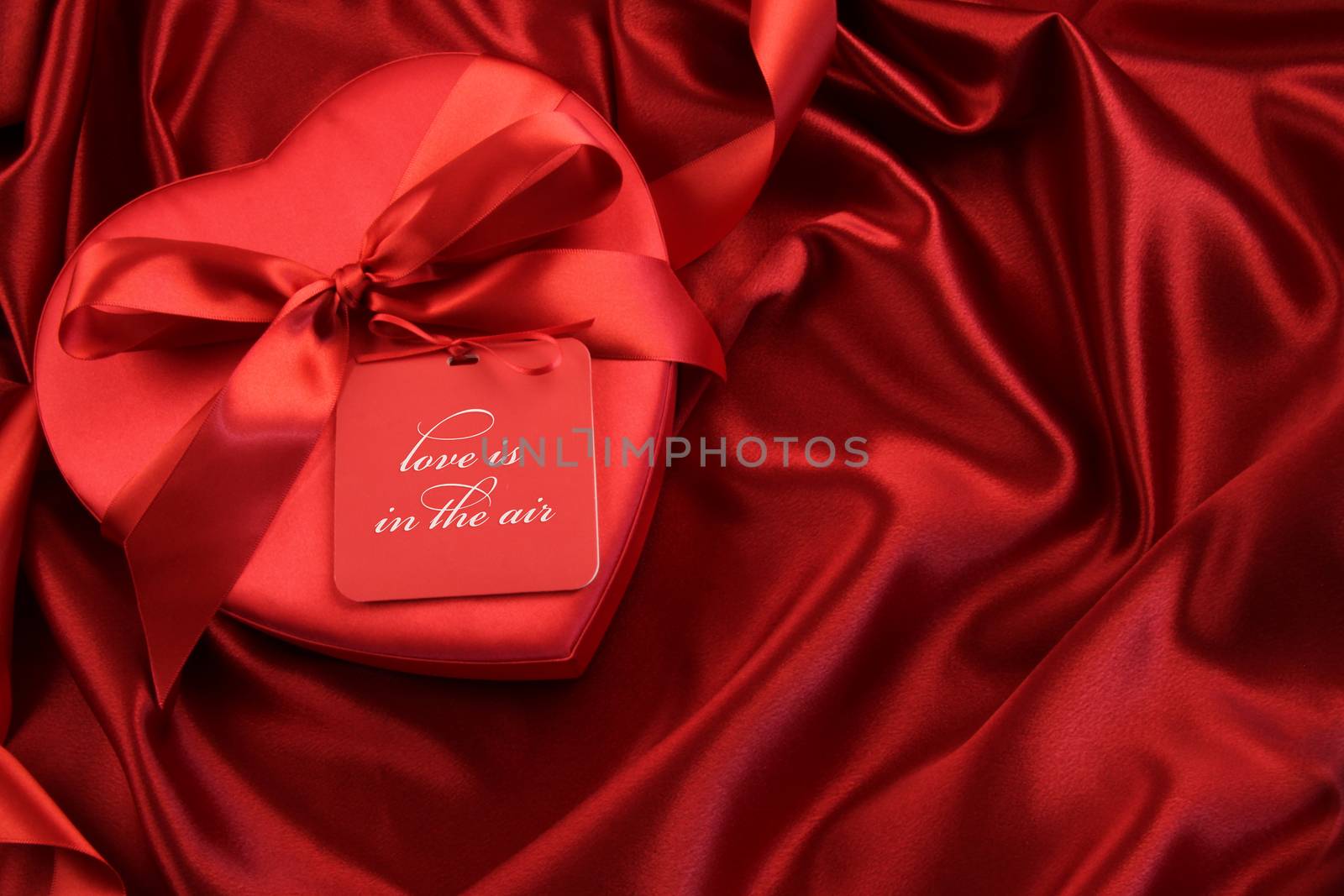 Chocolate box with gift card on satin background