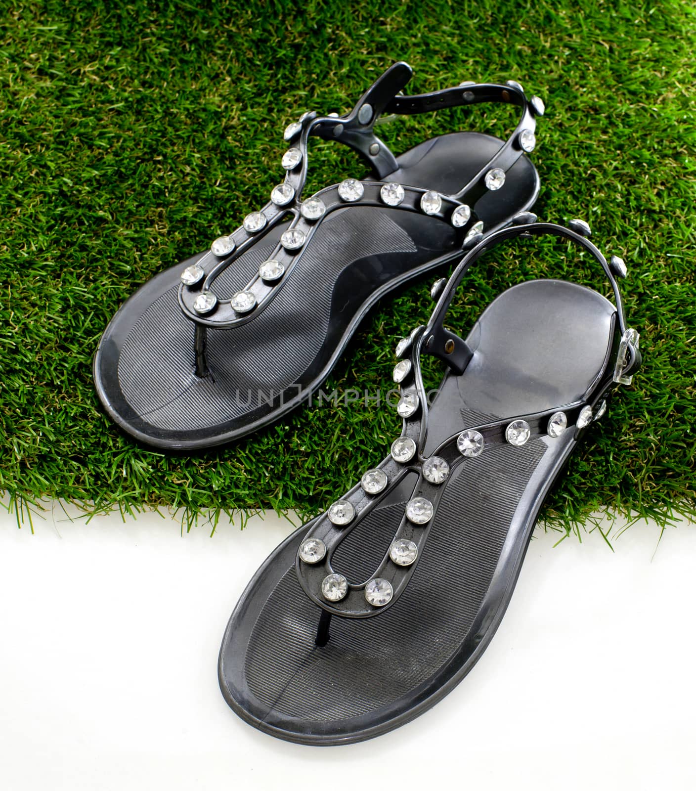 Sandals with rhinestones on green grass. View from above. Isolate on white.