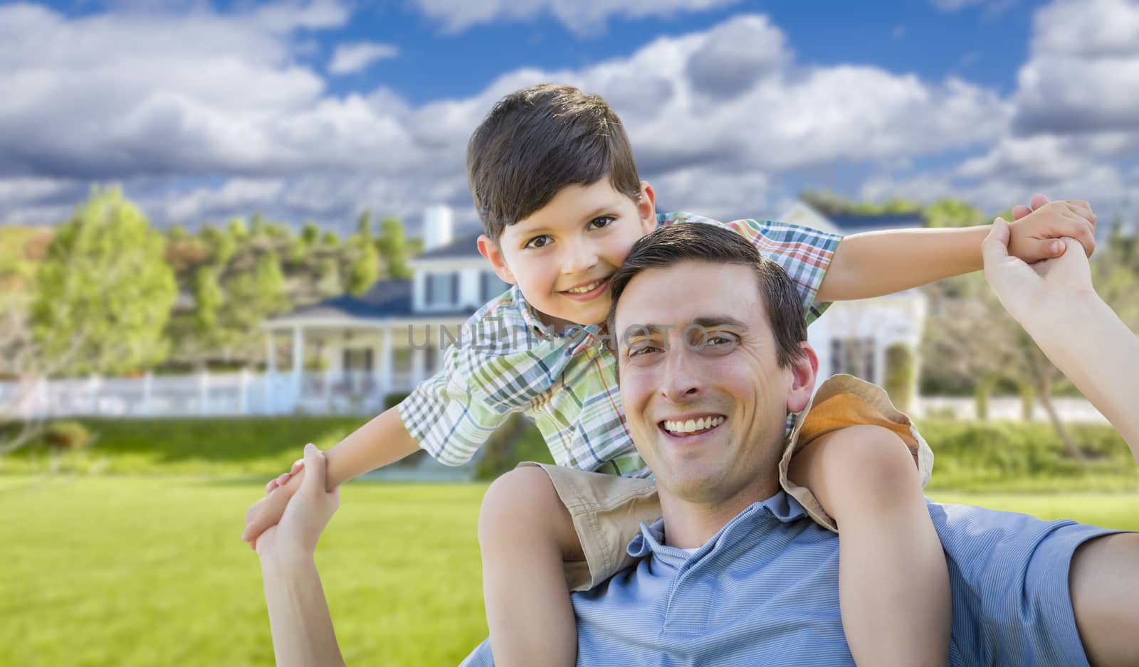 Mixed Race Father and Son Playing Piggyback in Front of Their House.