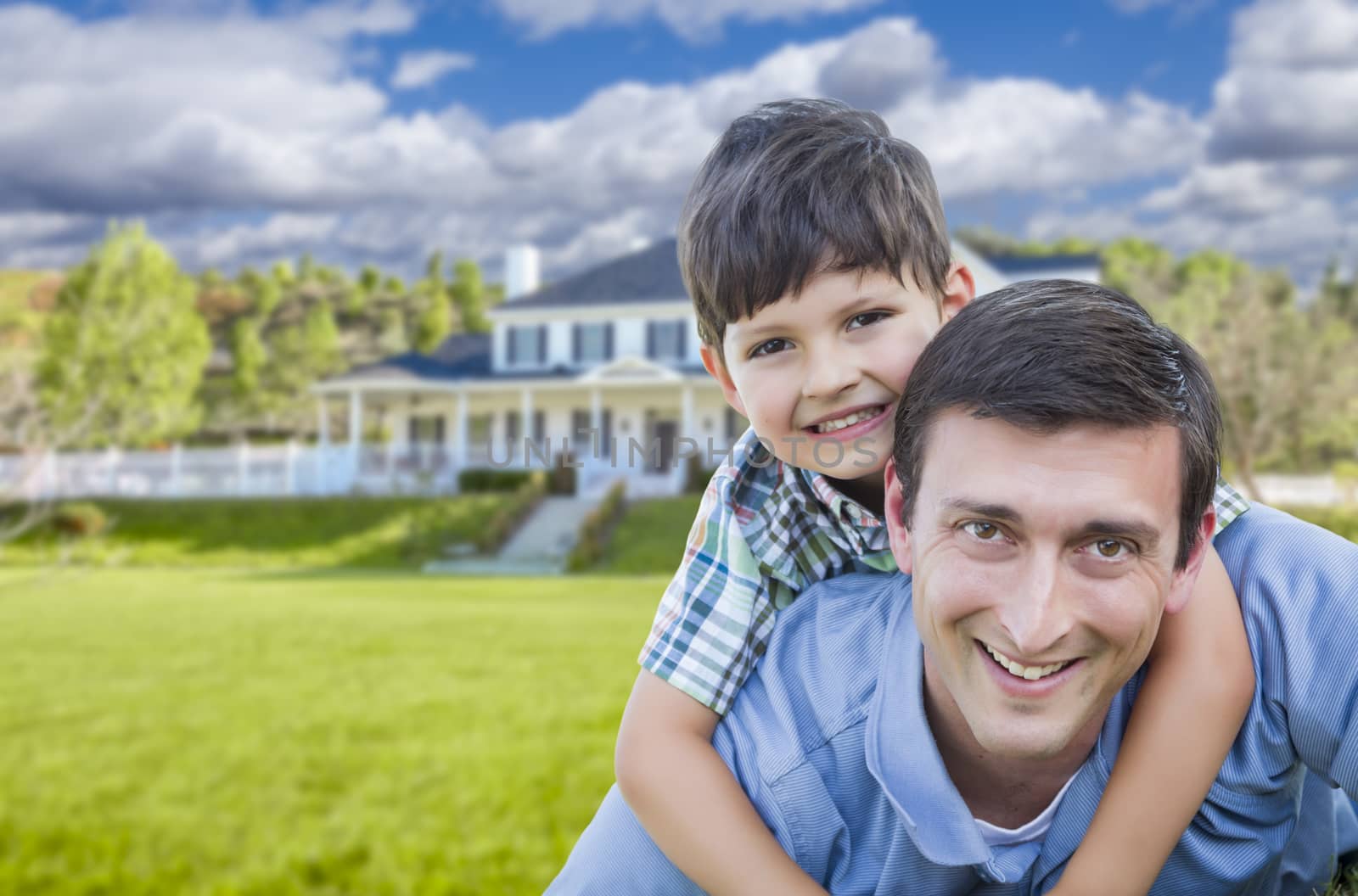 Mixed Race Father and Son Playing Piggyback in Front of Their House.