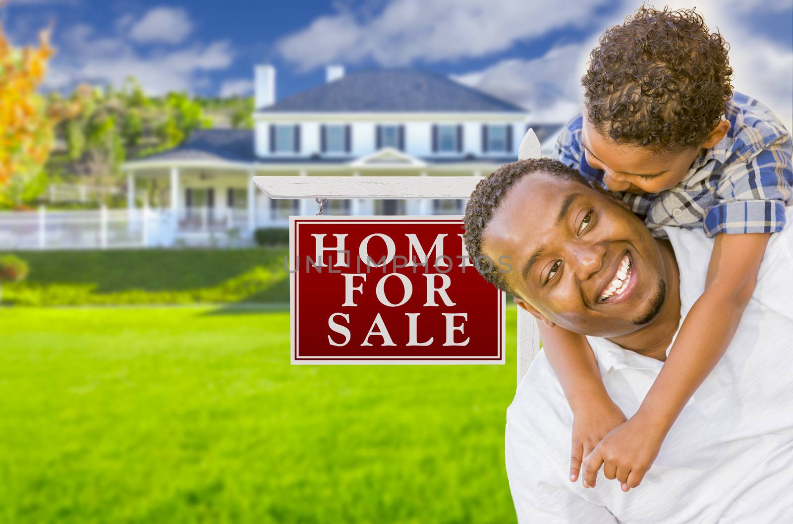 Happy Mixed Race Father and Son In Front of For Sale Real Estate Sign and New House.