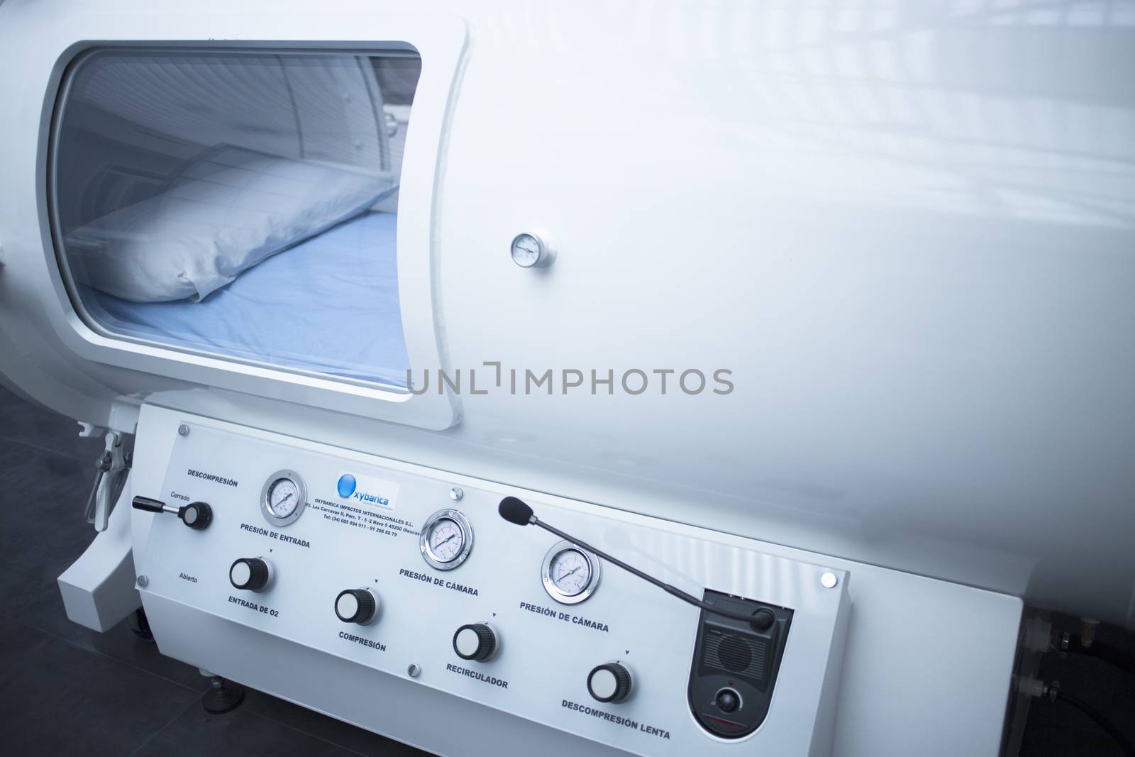 Hyperbaric Oxygen Therapy (HBOT) chamber tank used for specialised medical treatment for injuries in hospital clinic. Exterior viewing window with pillow and bed inside. 