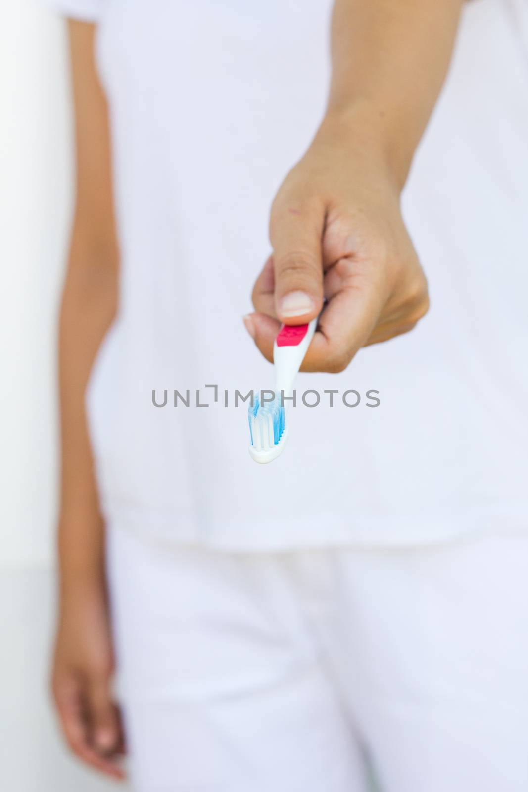 woman in white cloths holding toothbrush