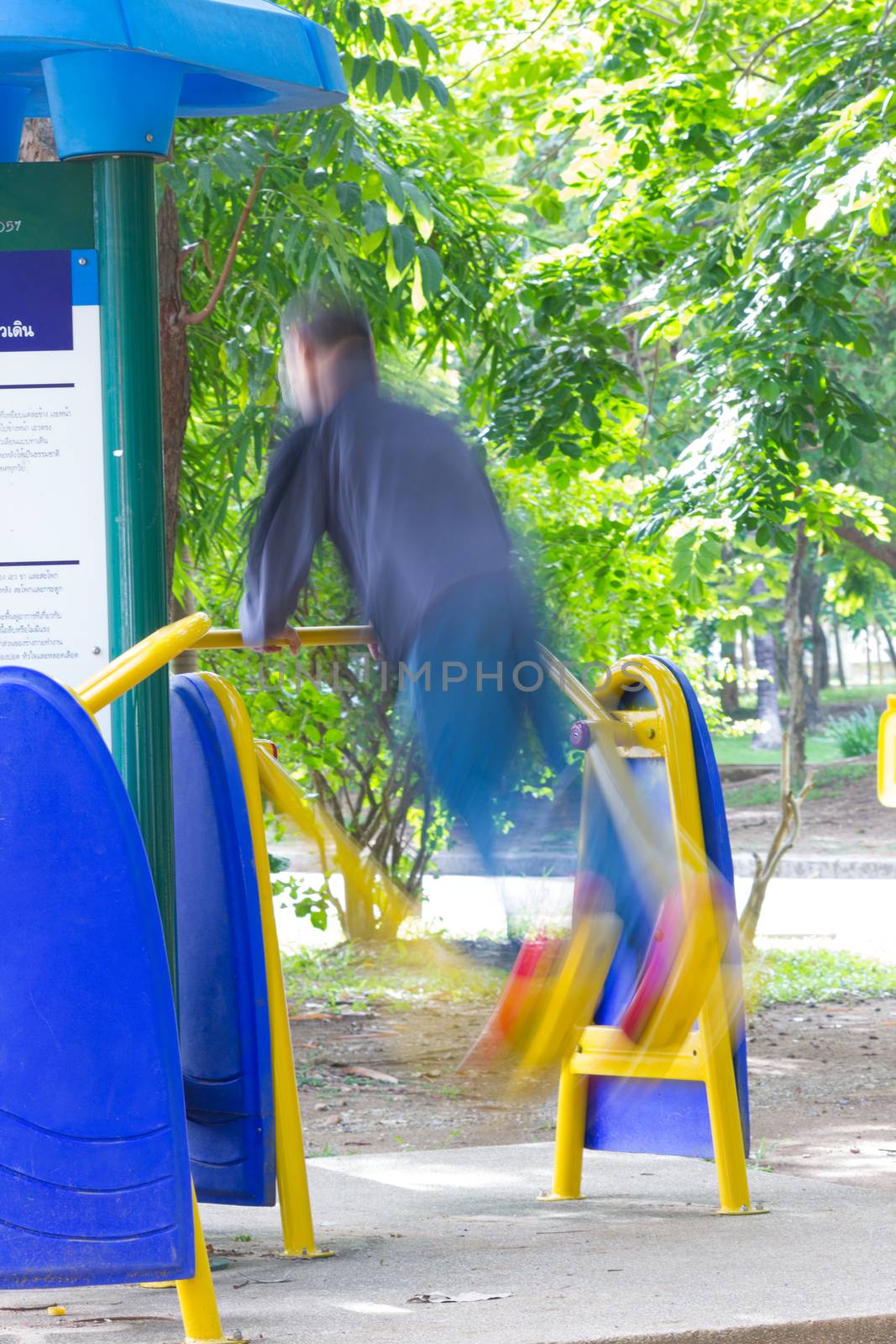 Blurred image of a man exercising on equipment in a park in Thai by a3701027