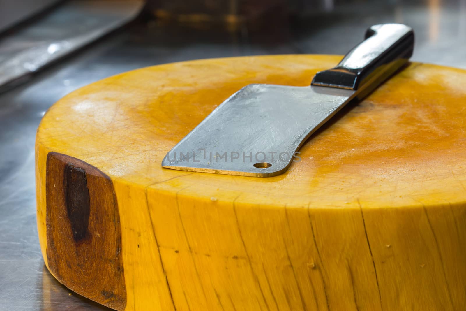 cleaver on yellow big chopping block in sidewalk restaurant in thailand