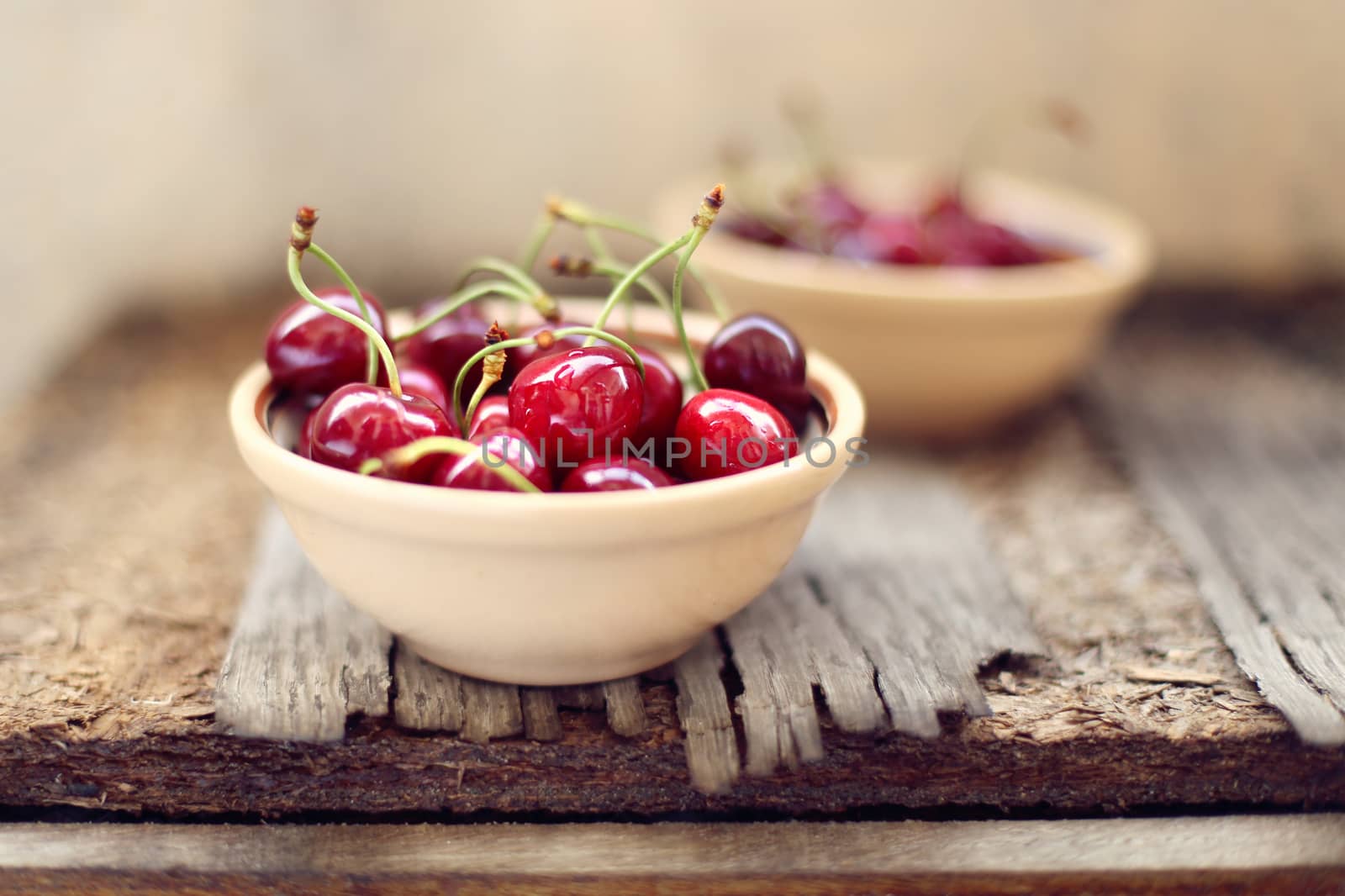 many ripe raw wet sweet cherry in dish on wooden background