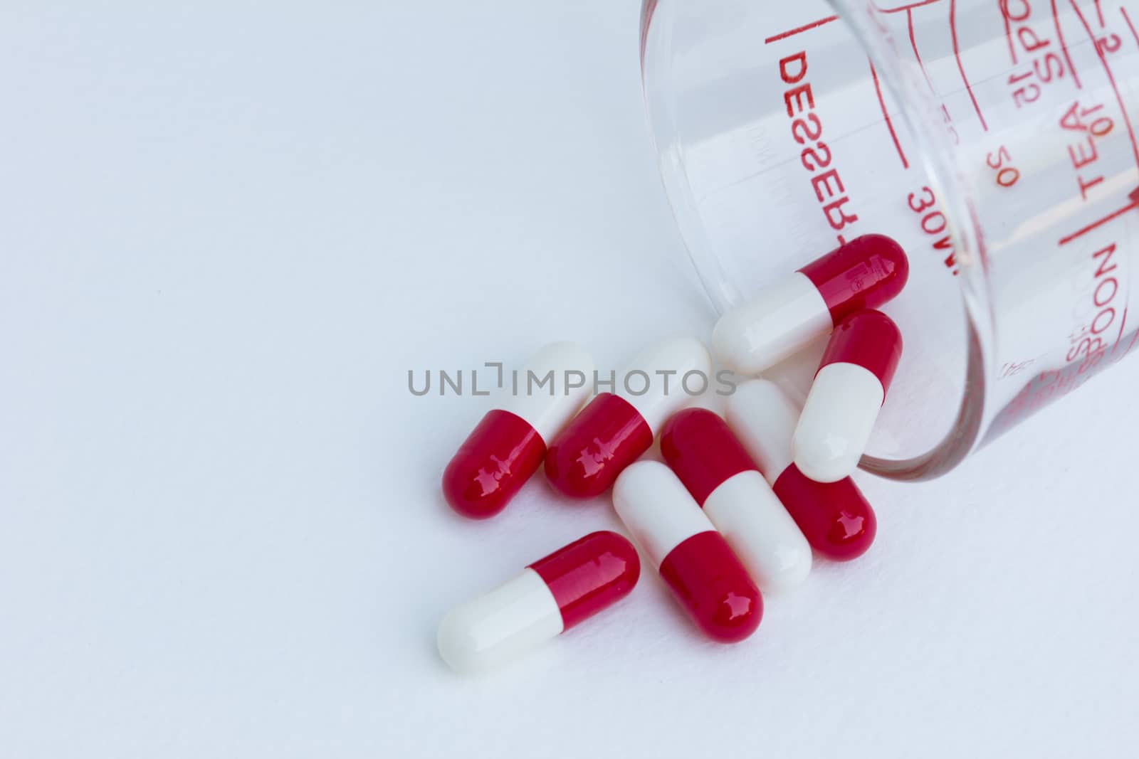 capsules with  measuring glass isolated on a white background