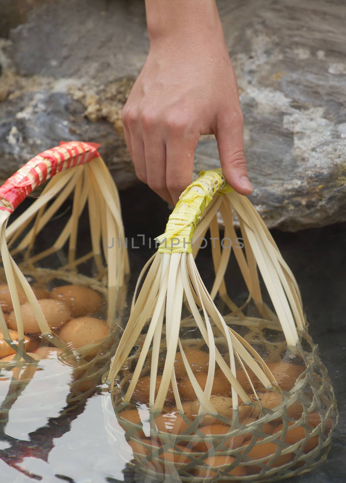 hand of a man boiling eggs on hot spring in Thailand