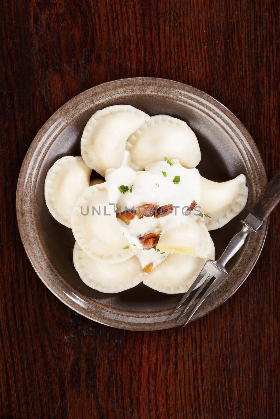 Bryndzove pirohy. Dumplings with sheep cheese bryndza on brown plate on brown wooden background. Traditional slovak food.