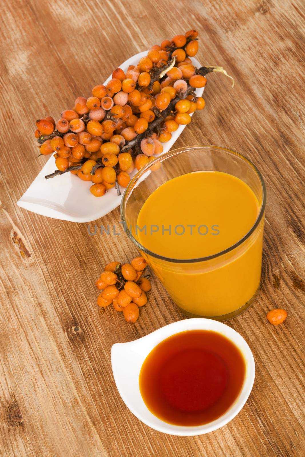 Sea buckthorn juice, oil and berries isolated on wooden background. Natural, healthy vitamin and detox.