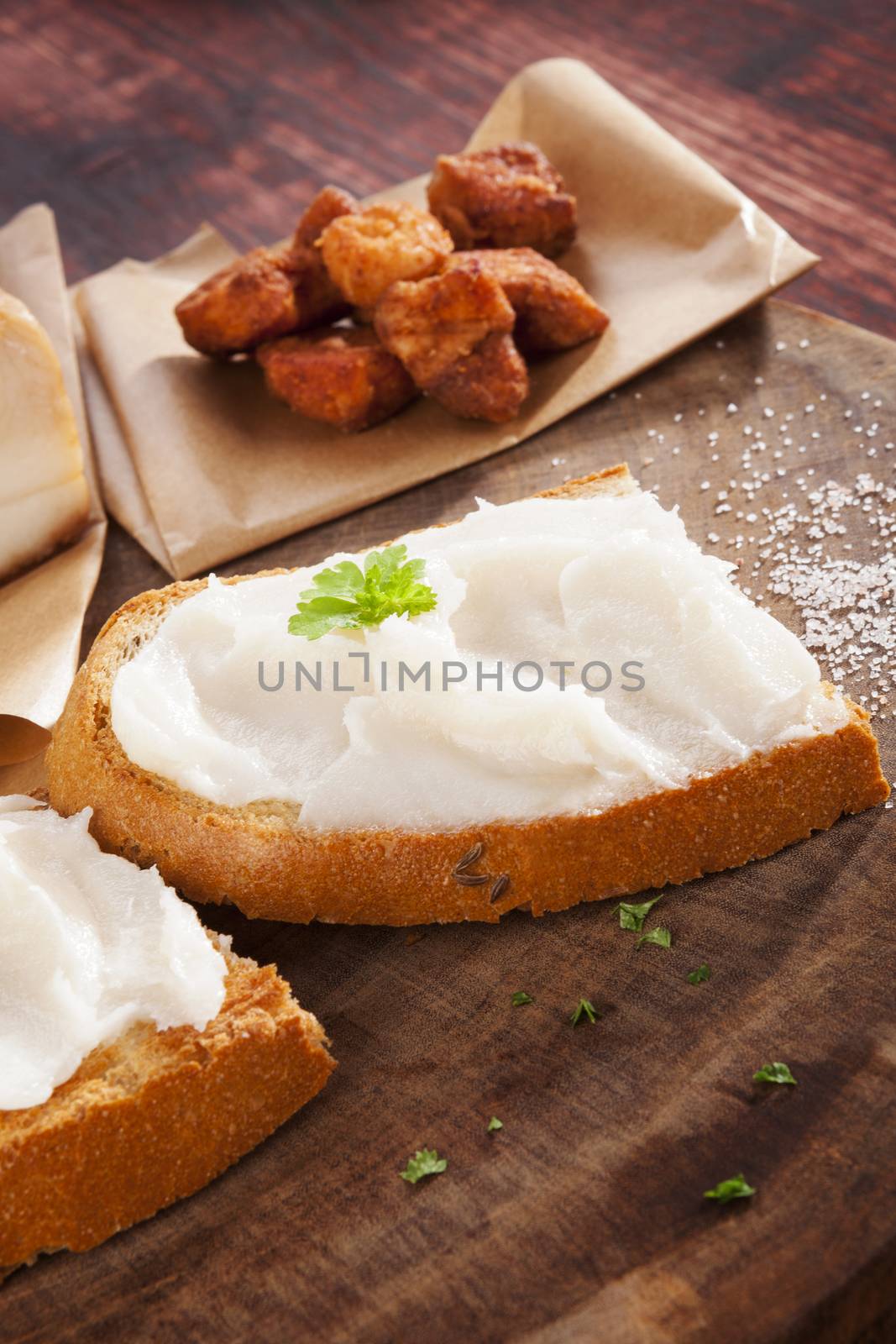 Bread with lard and pork scratchings on brown wooden background. Traditional british eating.