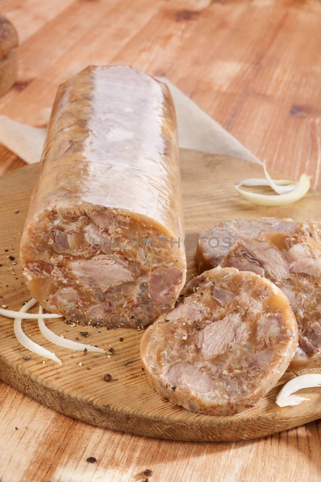Head cheese on brown vintage cutting board with onion. Traditional culinary eating. 