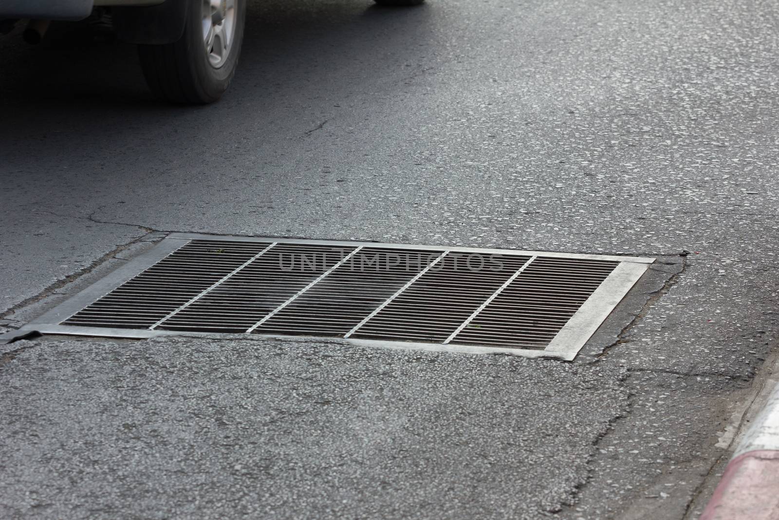 Drain grating on road in Thailand by a3701027