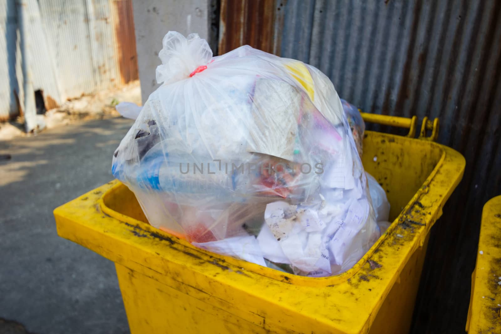 yellow bin full of rubbish in sidewalk in Thailand by a3701027