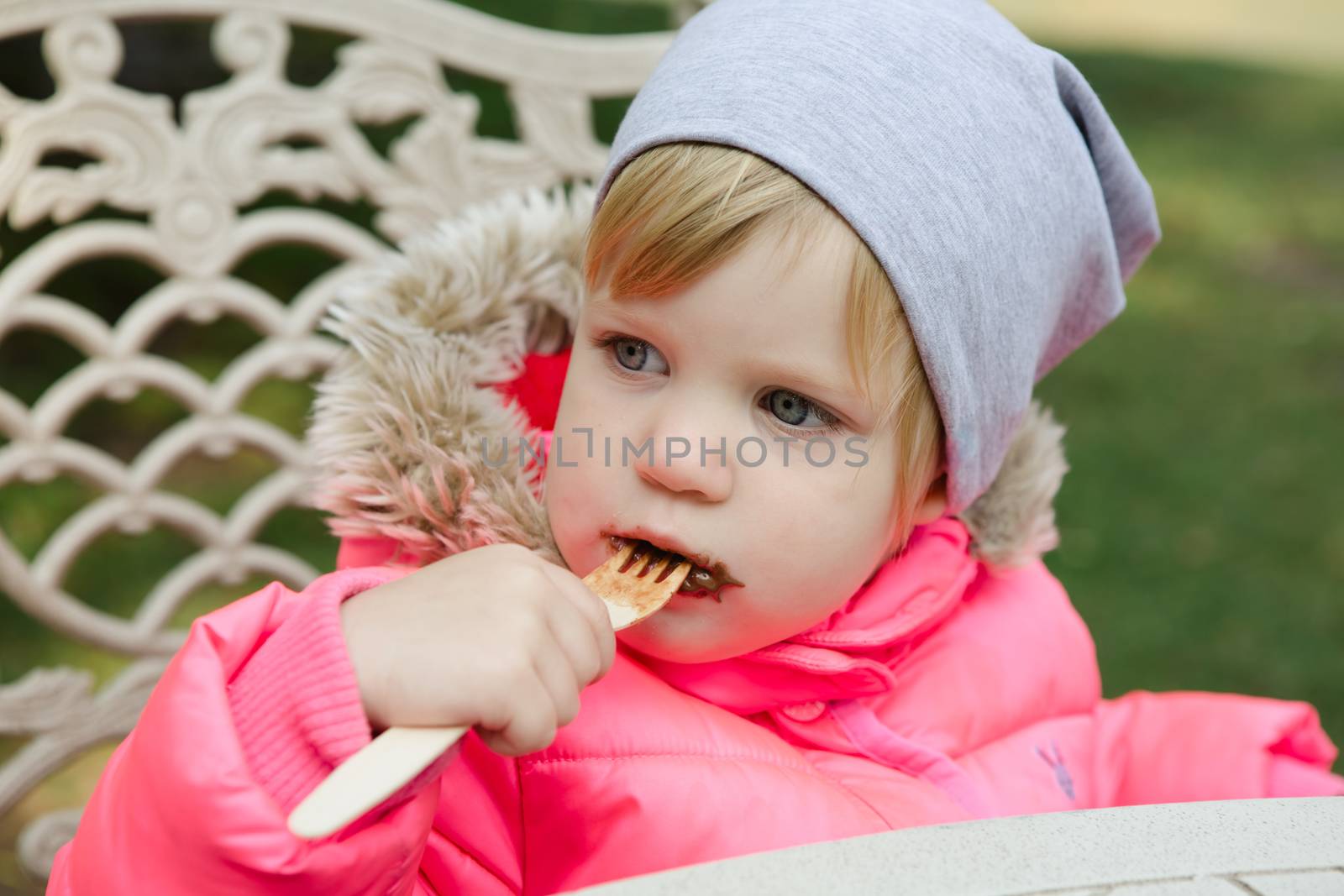 Child eating waffles with chocolate in park by sarymsakov
