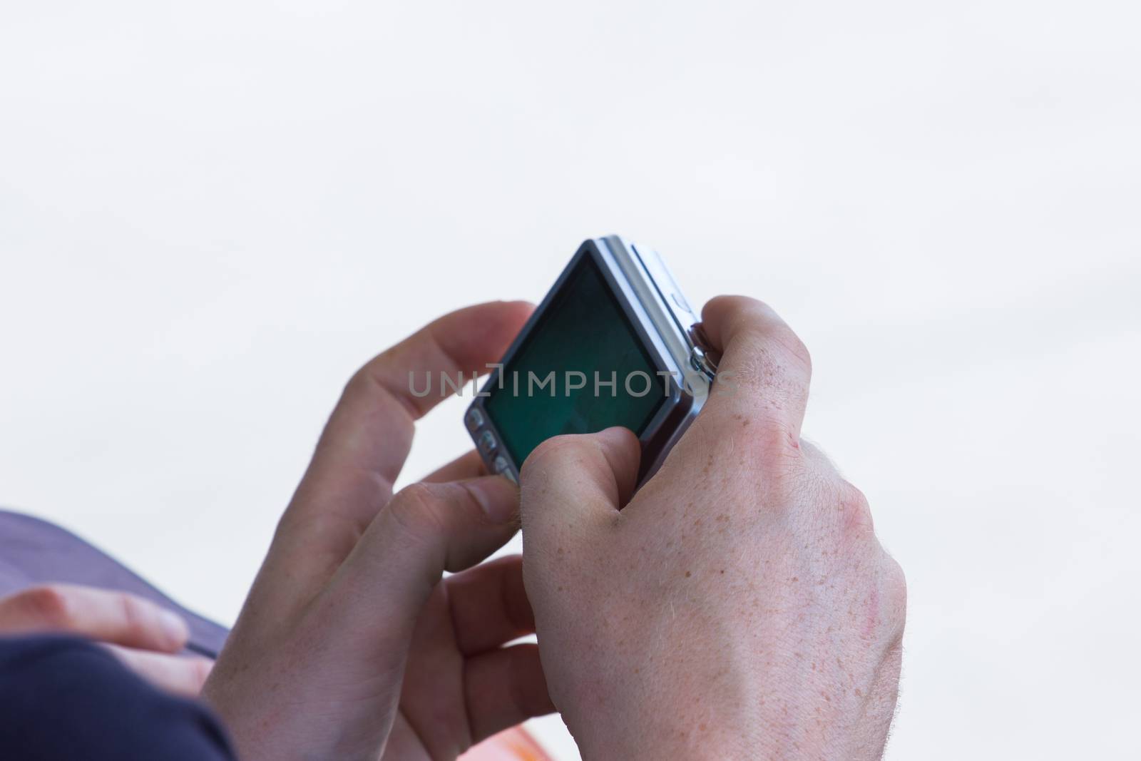 Closeup image of two hands holding black compact digital photo camera, isolated on white background