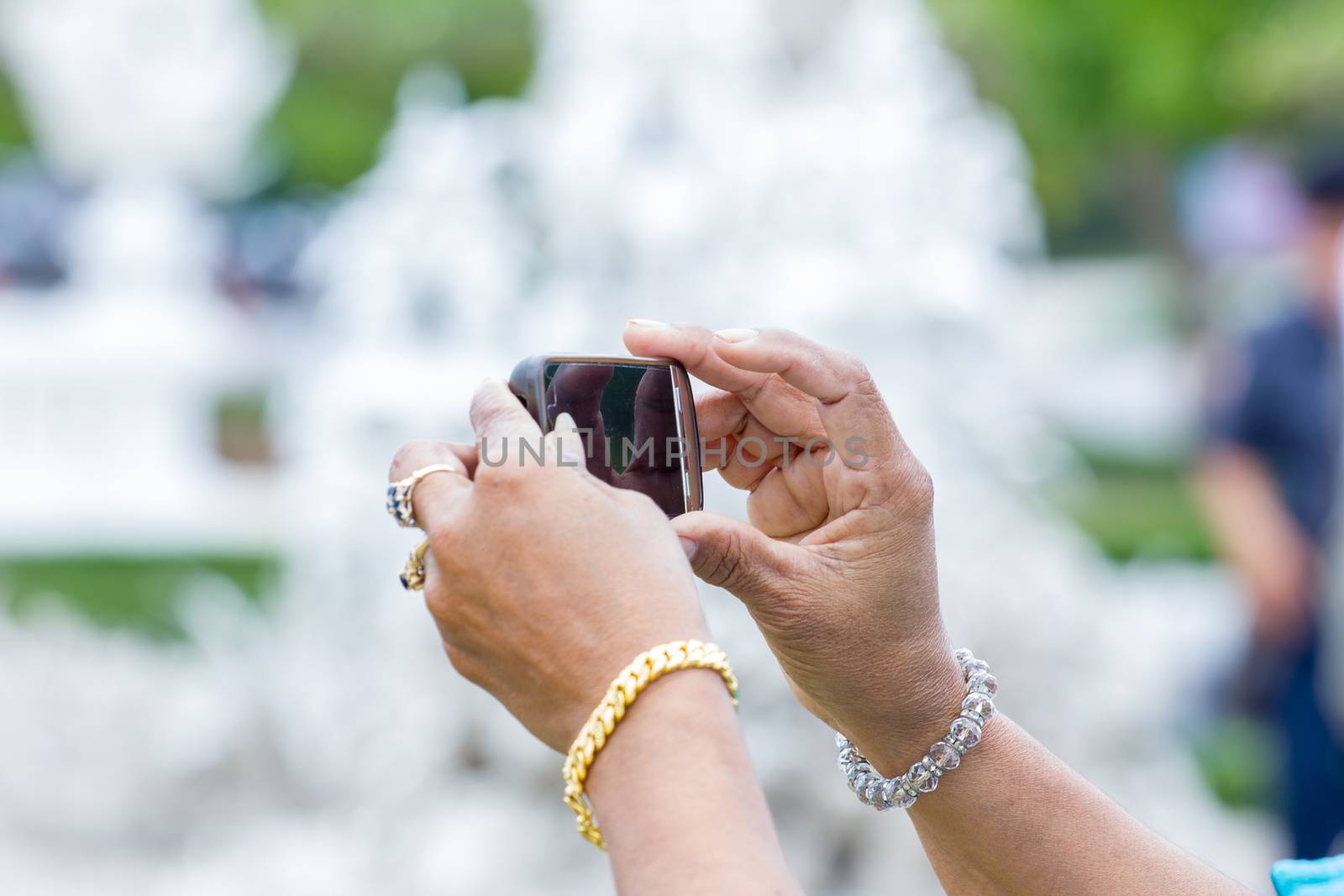 rich woman hands taking a picture at a temple in Thailand