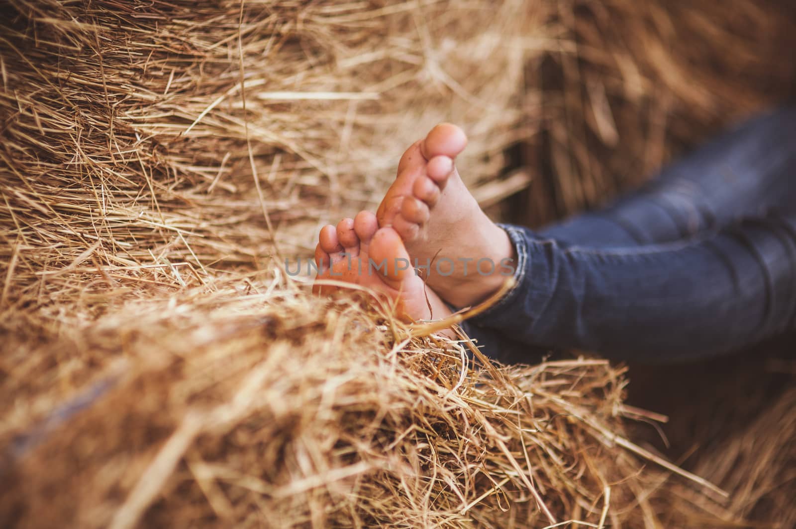 barefoot girl legs on haystack by fesenko