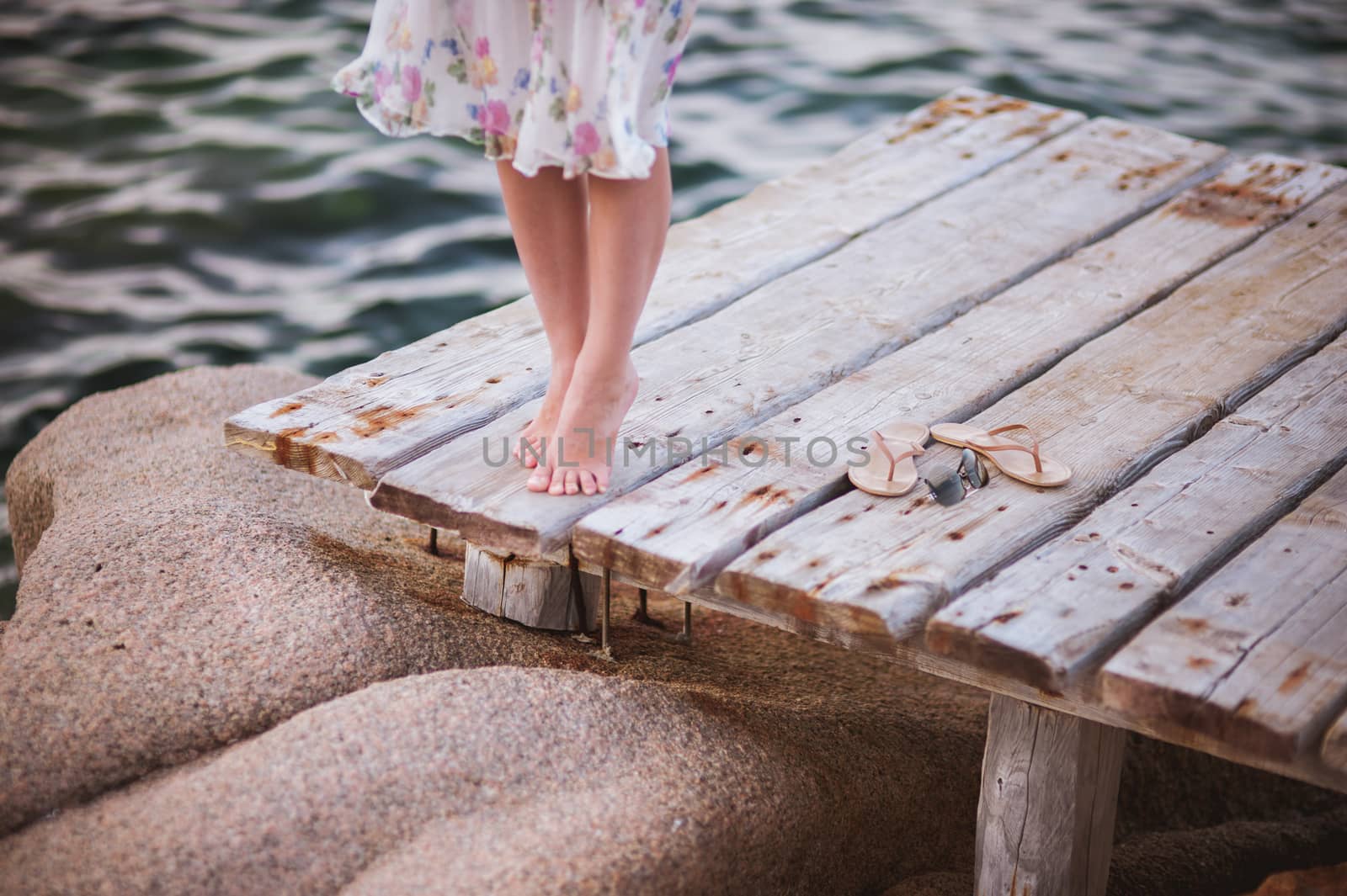 barefoot girl on wooden bridge above water no face 
