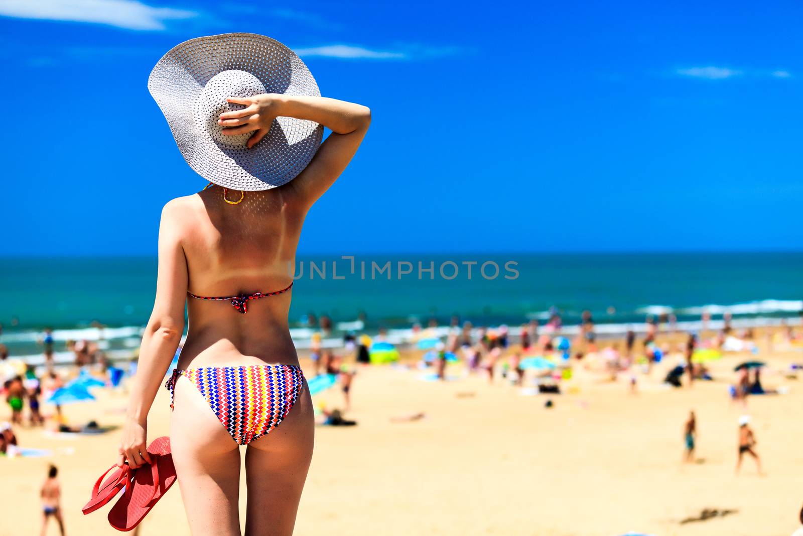 Woman in big sunhat on a beach by Nobilior