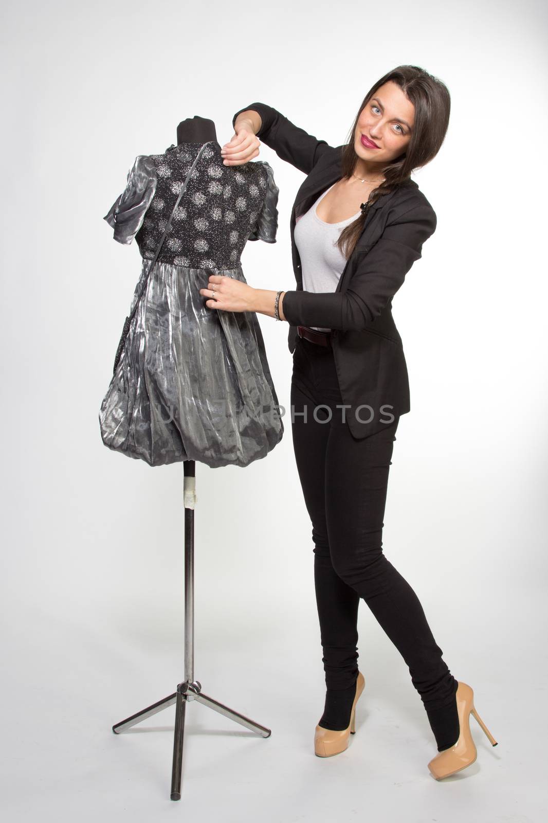 Woman decorating dressed mannequin in silver dress