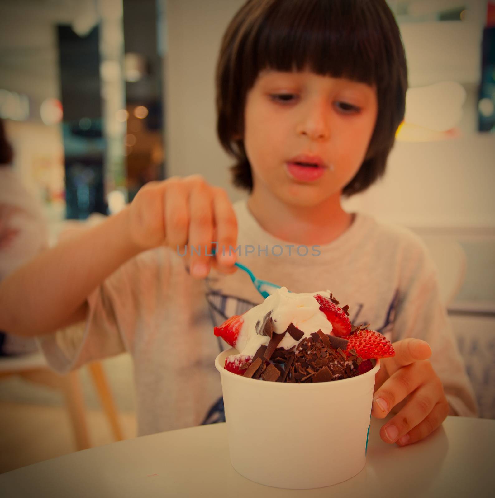 boy eating ice cream with chocolate and strawberries, instargram filter style, editorial use only