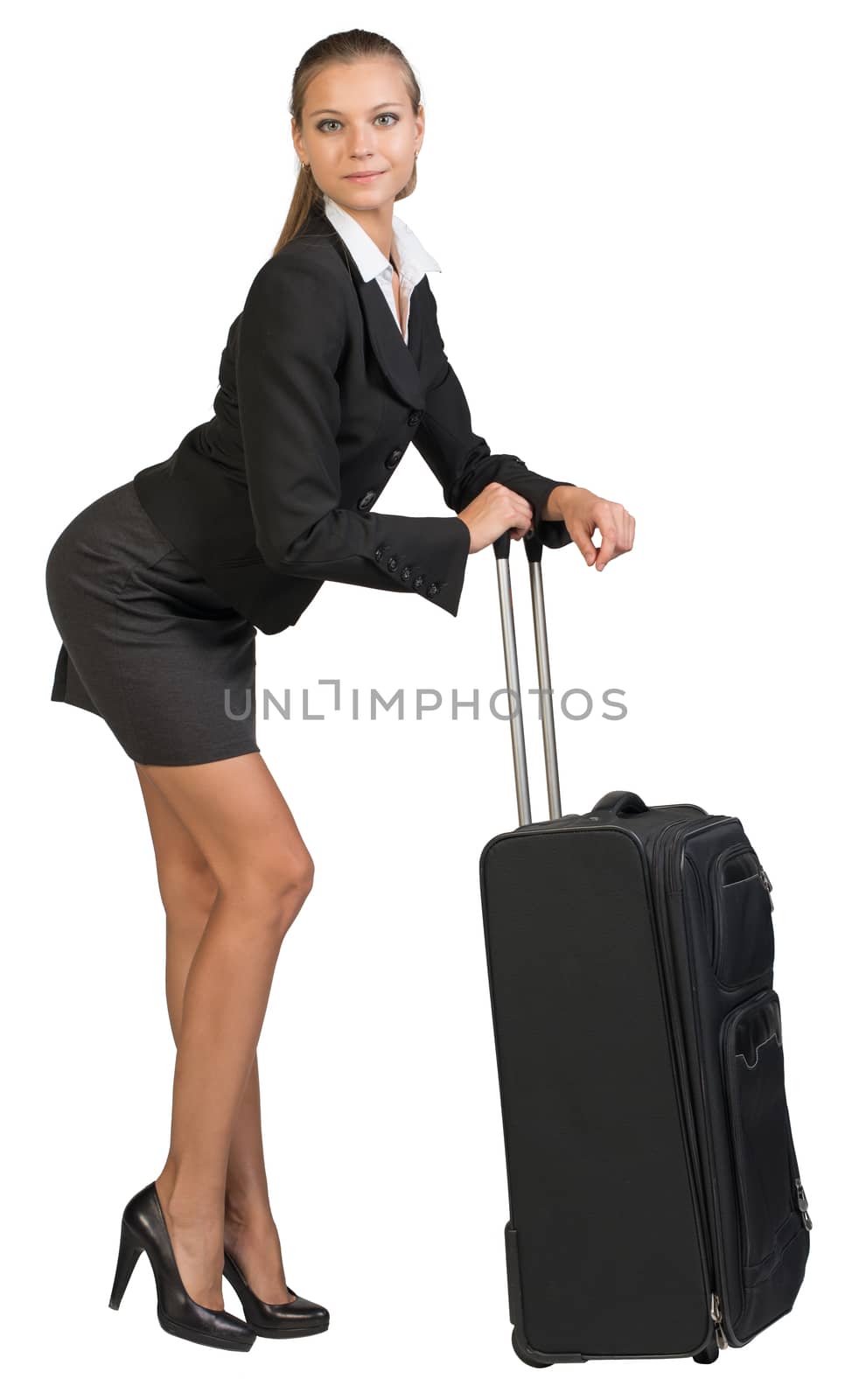 Businesswoman bending forward leaning on extended handle of wheeled suitcase, looking at camera. Isolated over white background
