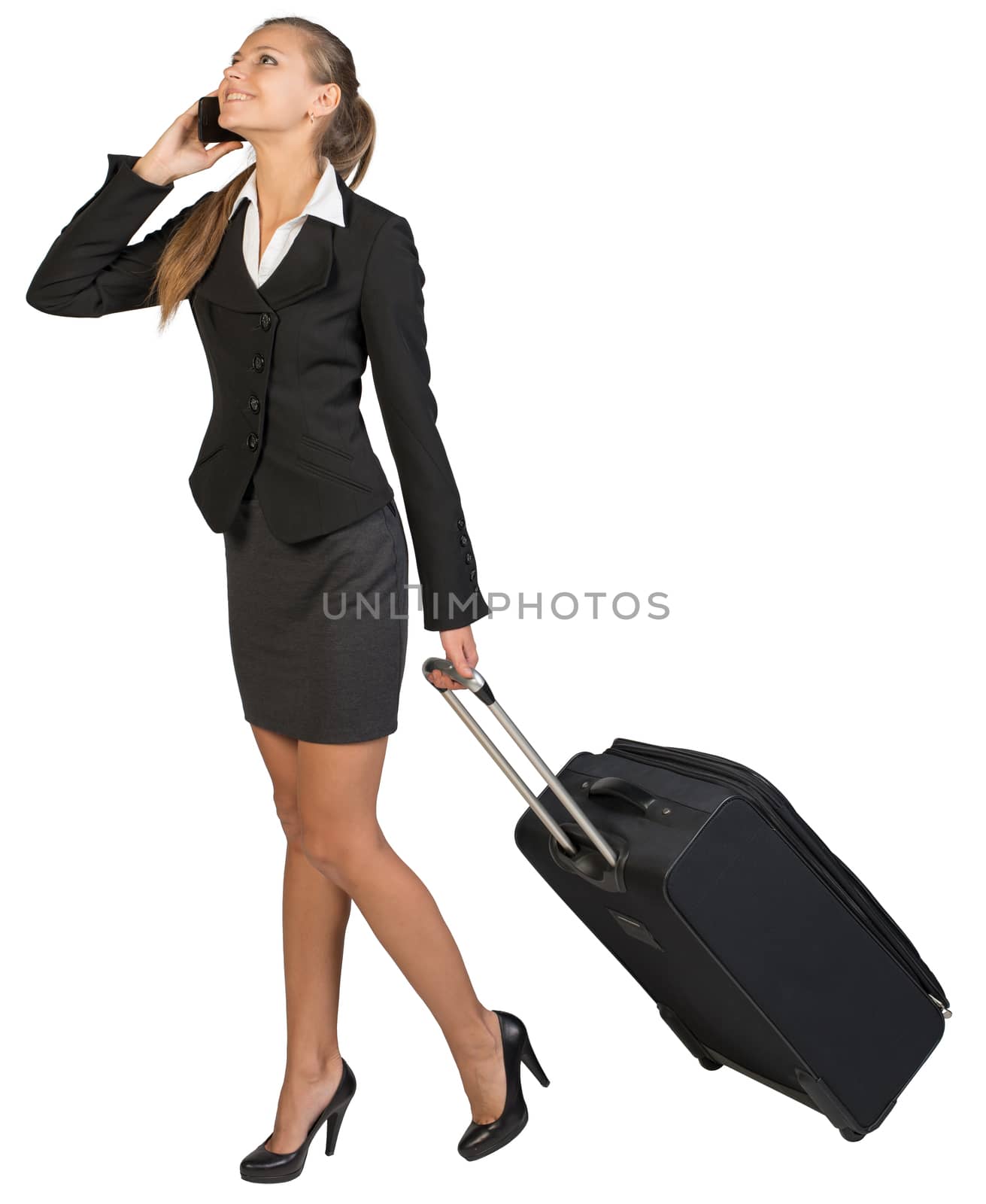 Businesswoman walking with wheeled suitcase, talking on the phone, smiling. Isolated over white background