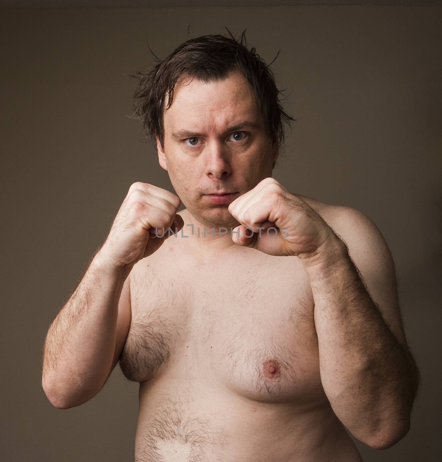 Naked man holding up his hands trying to fight