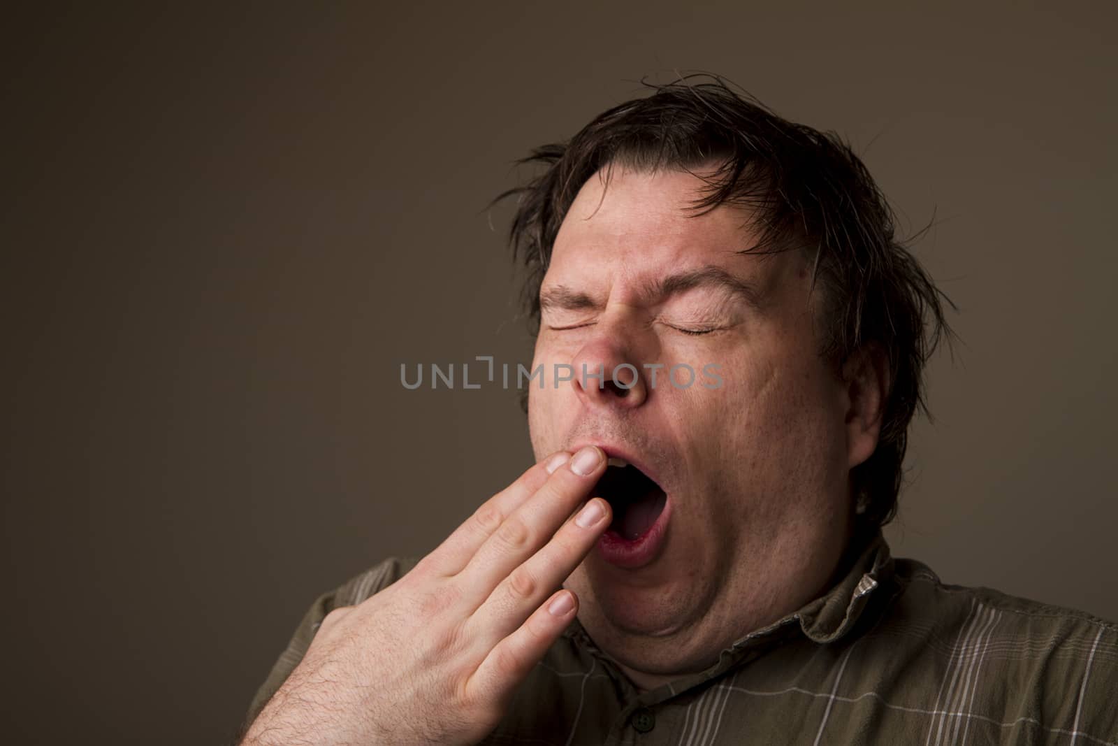 MAn lets out a huge yawn with how tired he is, or is he getting ready to sneeze