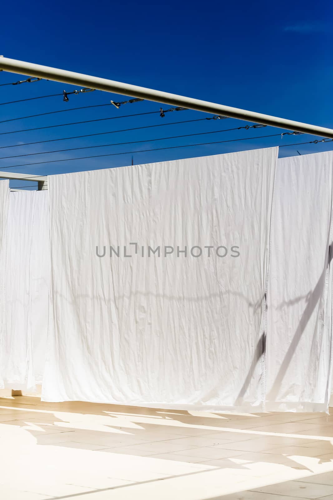 White clothes hanging on the line against blue sky.