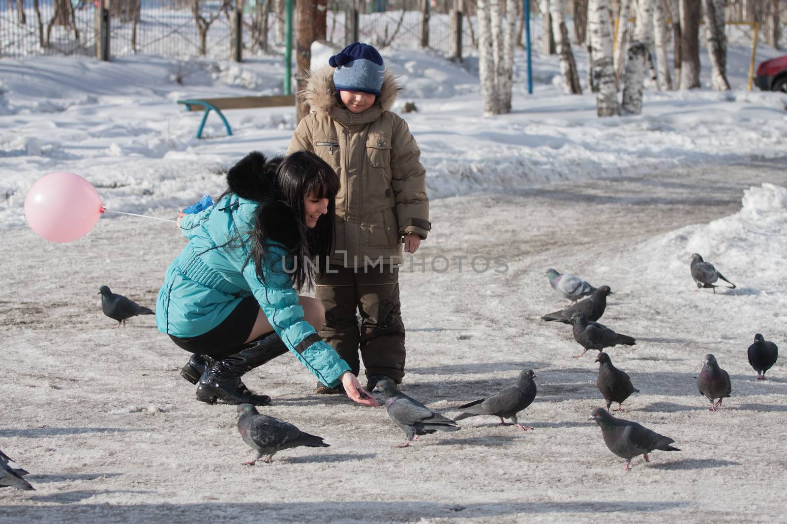 children, boy and girl in winter feeding pigeons