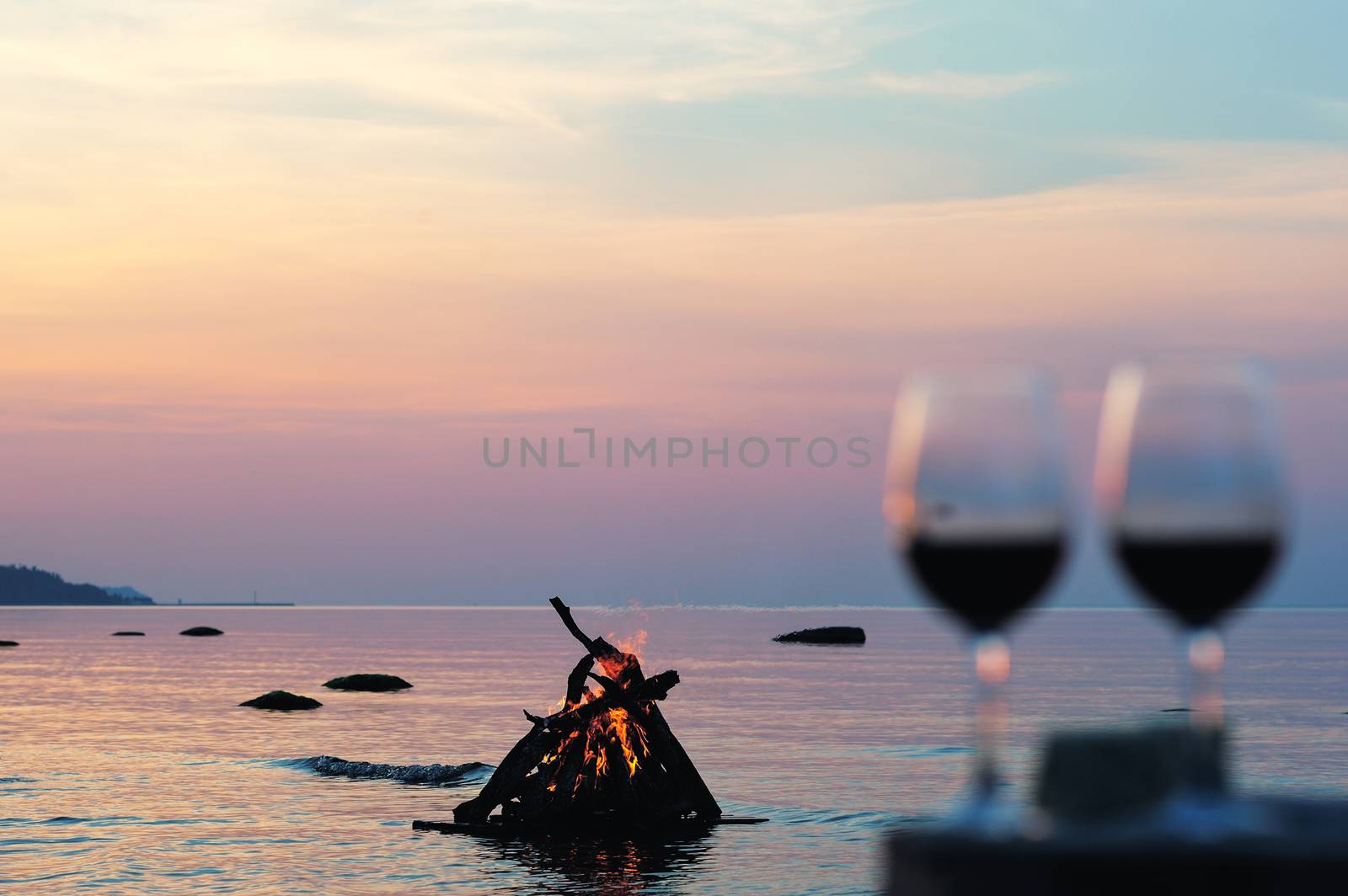 Campfire and wine glasses with wine on the coast